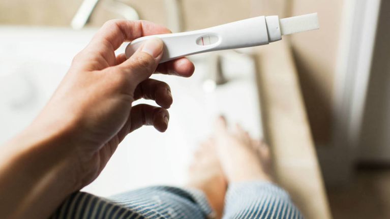 A woman looking at a faint line on a pregnancy test