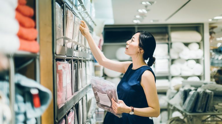 Smiling young pregnant woman shopping for home necessities in shop