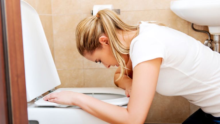 Side View Of Woman Vomiting In Bathroom At Home