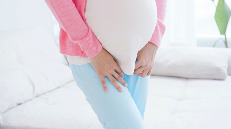 close up of pregnant woman urine urgency at home