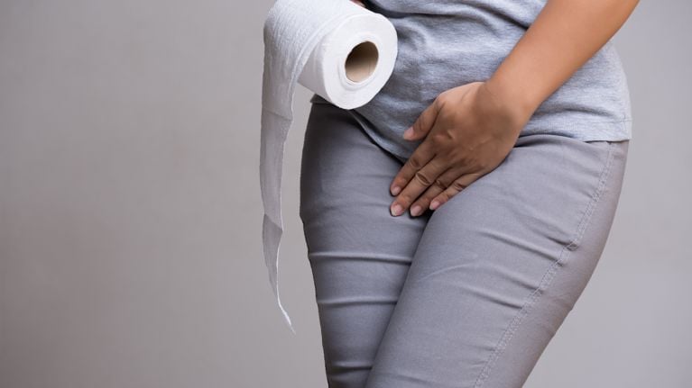 Woman hand holding her crotch lower abdomen and tissue or toilet paper roll. Disorder, Diarrhea, incontinence. Healthcare concept.