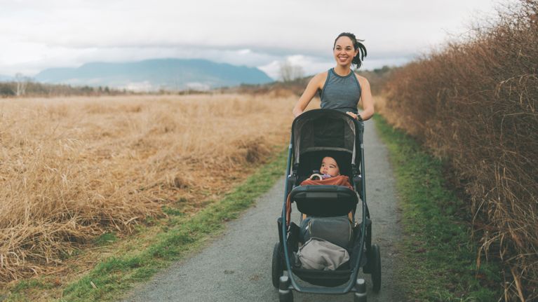 Smiling Mother With Baby Walking On Road