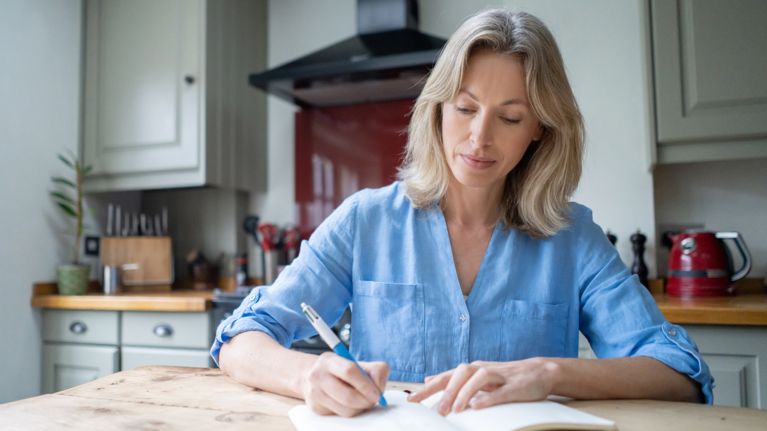 Portrait of a beautiful adult woman at home writing on her journal