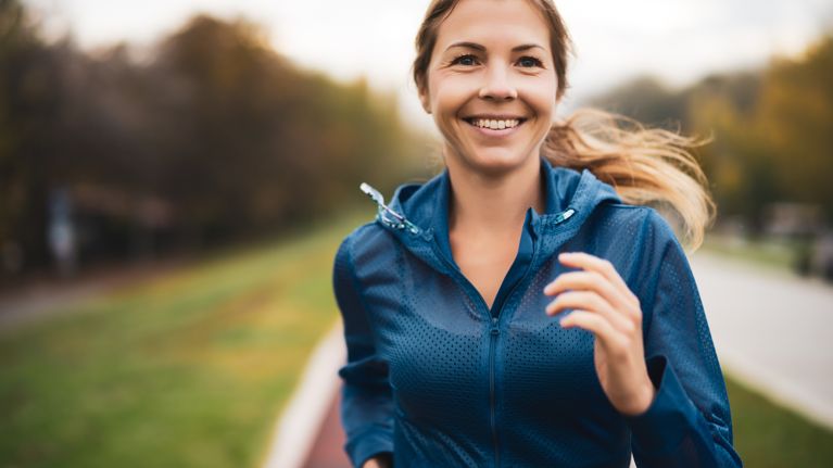 Beautiful adult woman is jogging outdoor on cloudy day in autumn.