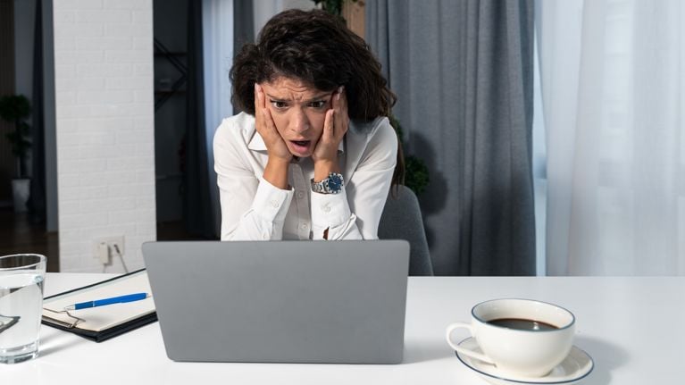 Young successful business woman is sitting in the modern office at work and is shocked by the results she received on her laptop computer about the company business for the past period