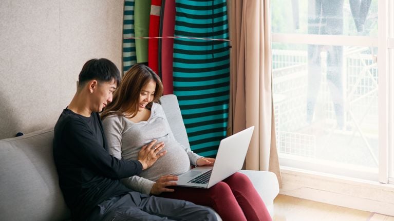 Couple of surfers using laptop,View from behind it.