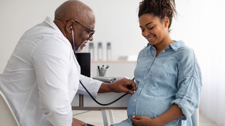 Gynecology Consultation. Smiling pregnant woman visiting her obstetrician doctor in maternity clinic,