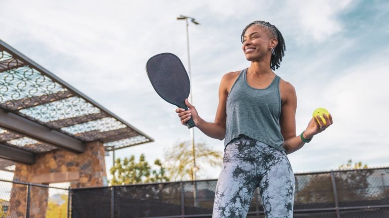 woman holding pickle ball racket and ball