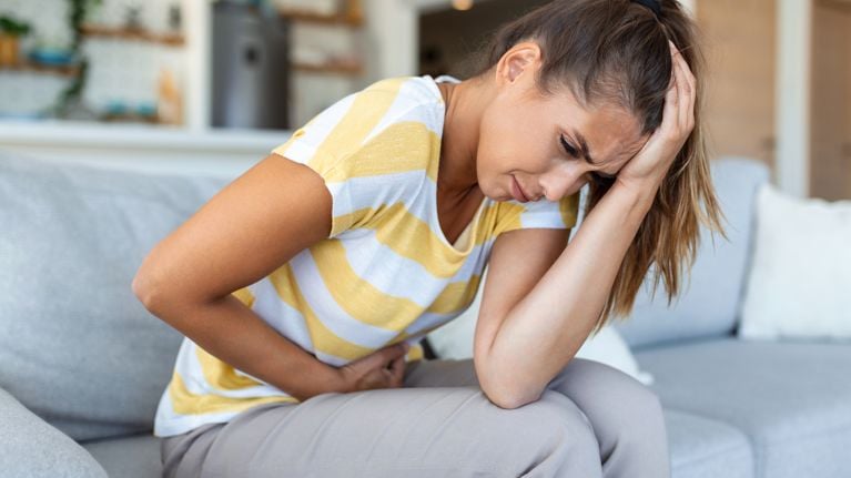 Woman lying on sofa looking sick in the living room.