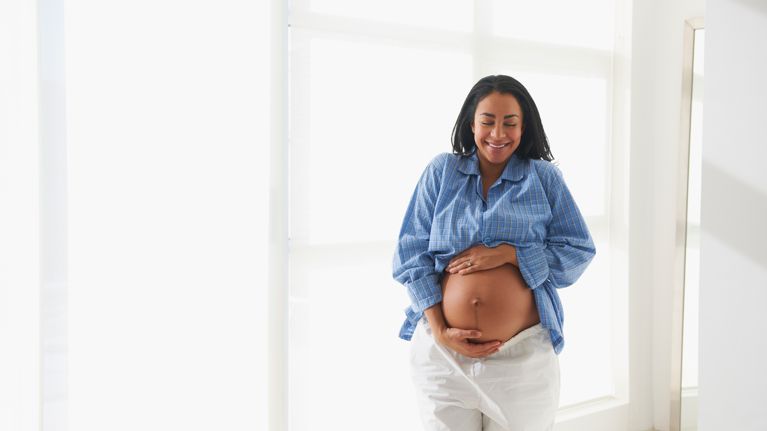 Smiling pregnant woman holding stomach