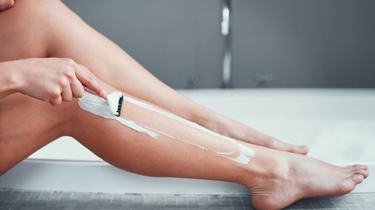 Closeup shot of an unrecognizable woman shaving her legs in the bathroom at home