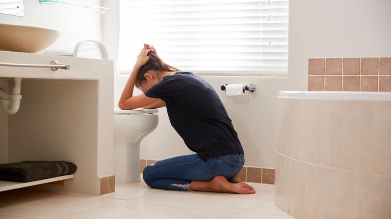 Woman Suffering With Morning Sickness In Bathroom At Home