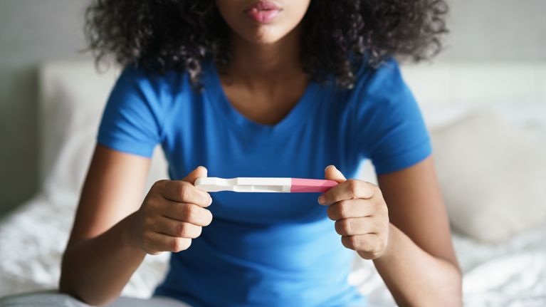 Disappointed girl getting unexpected result from pregnancy test kit.