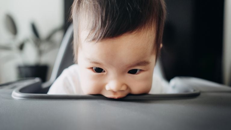 Playful baby biting the high chair table