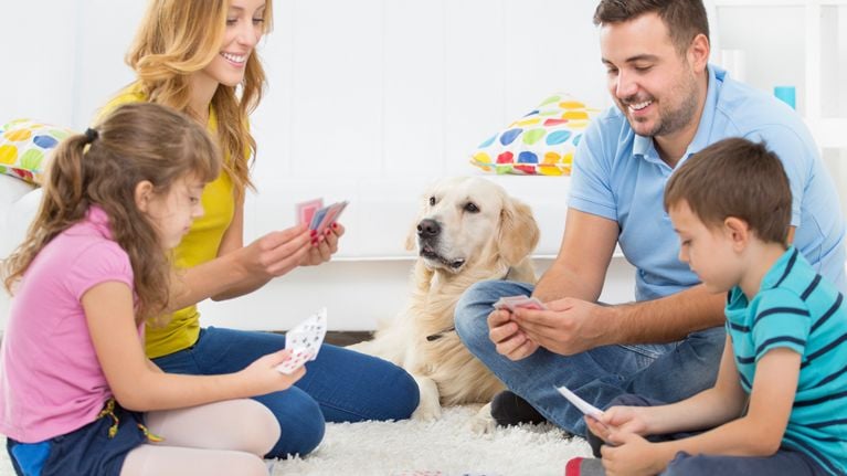 Family plays a card game on the carpet