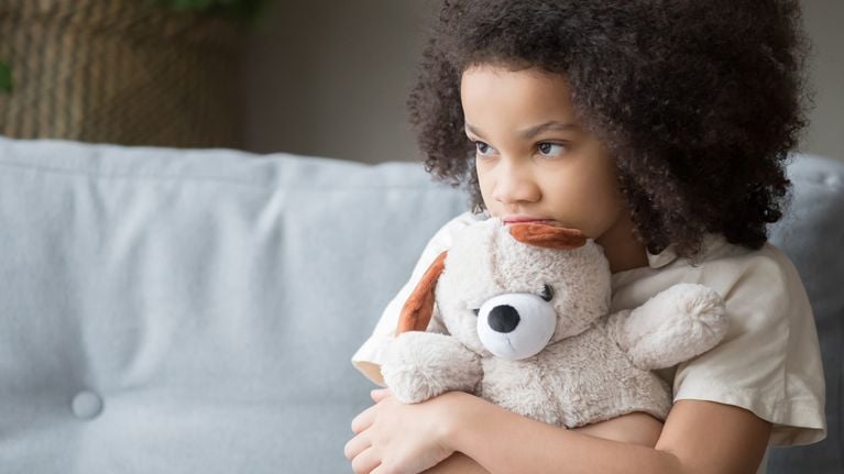 A girl hugs a teddy bear.