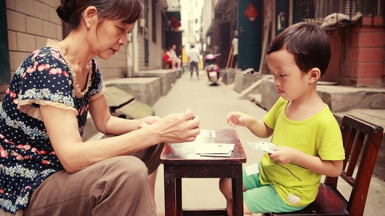 Little boy plays cards with older woman outside