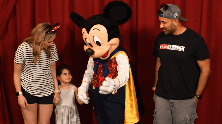 Author Megan with husband and daughter meeting Mickey Mouse