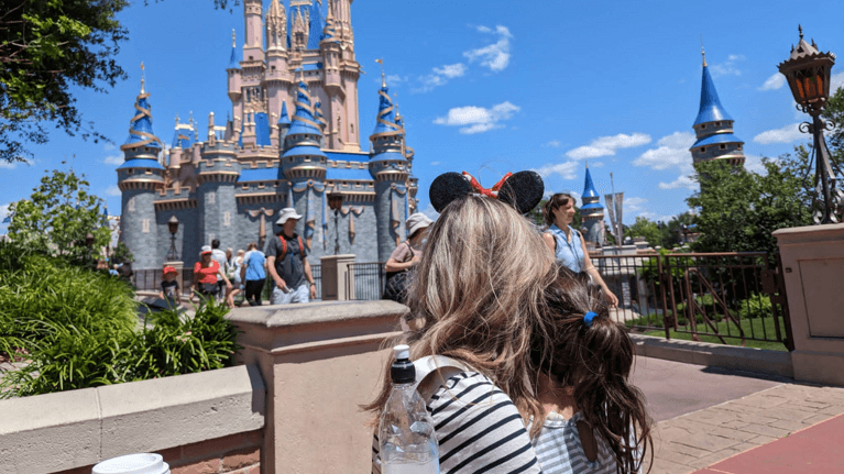 author Megan with her daughter sitting in front of the castle at magic kingdom looking at it