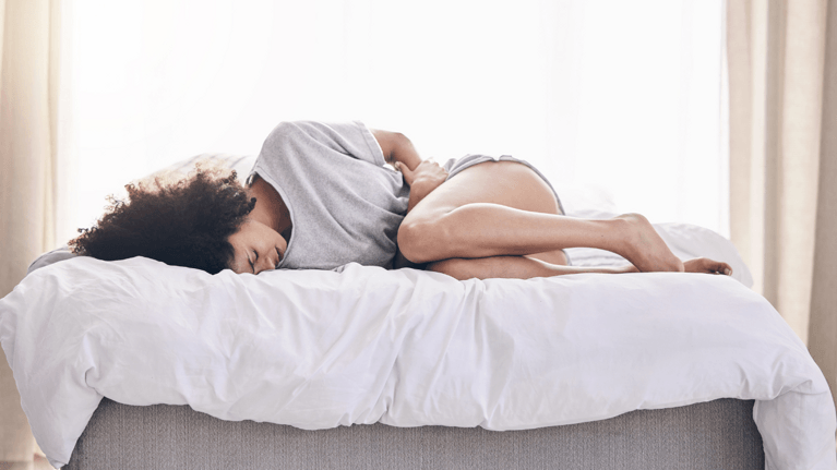 woman laying down clutching torso in pain