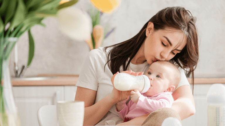 mom holding baby and feeding her a bottle of milk