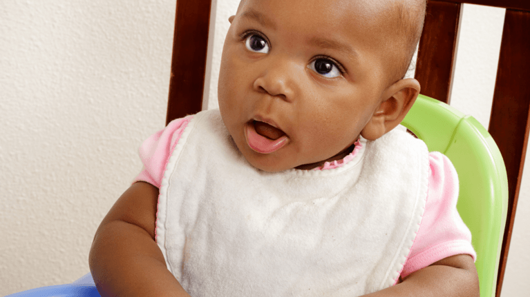 baby in a highchair eating cereal