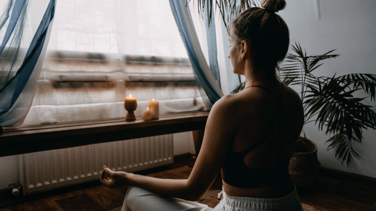 woman meditating in front of a window