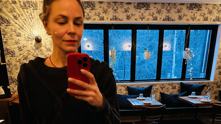 author Kyla fix taking a photo in a mirror in a restaurant