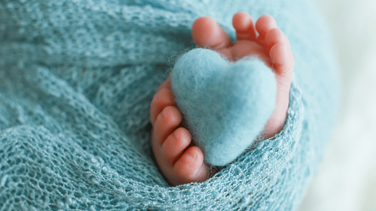 newborn baby feet being held in the shape of a heart