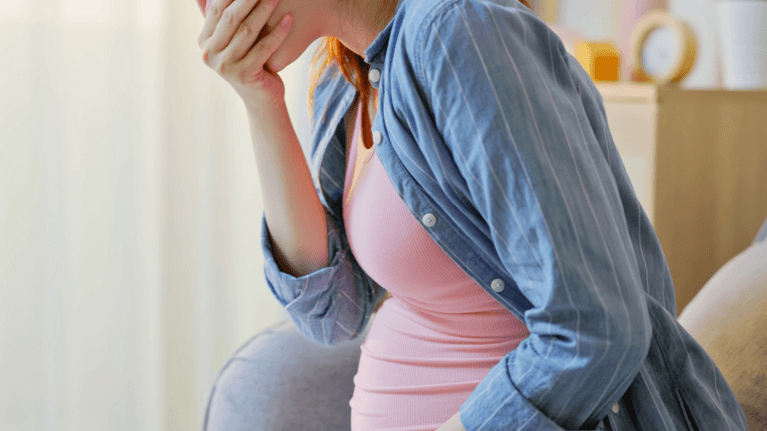 pregnant woman leaning over looking about to be sick
