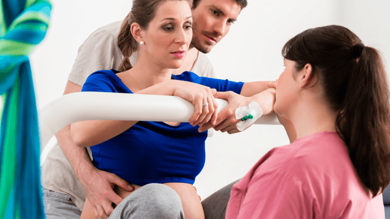 woman in labour with a support person behind her and a nurse