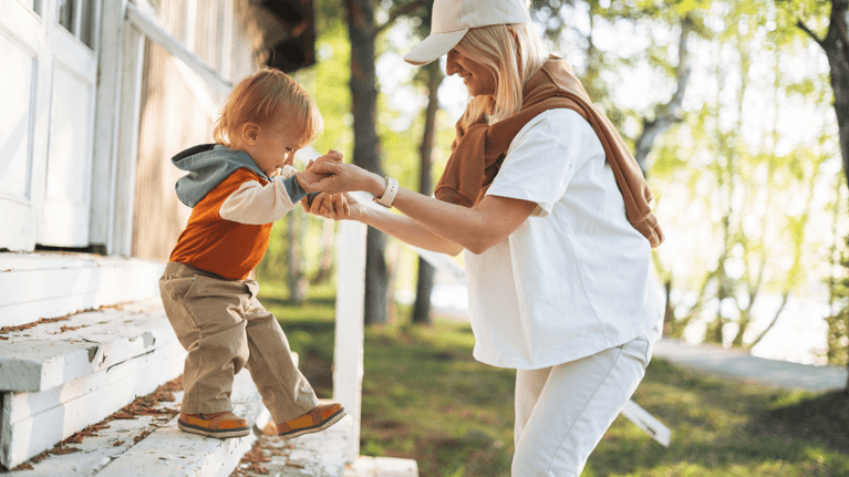 Mom helping son walk down front porch steps