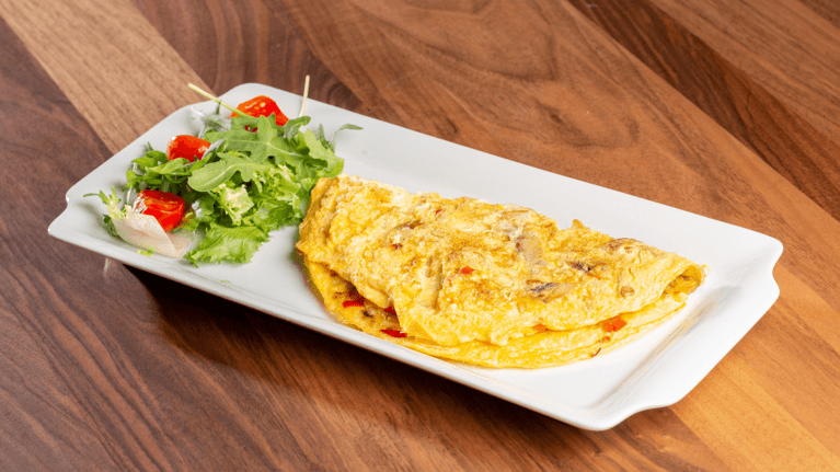 omlette sitting on a plate with a small salad