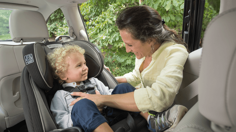 Mom buckling a toddler into a rear facing car seat