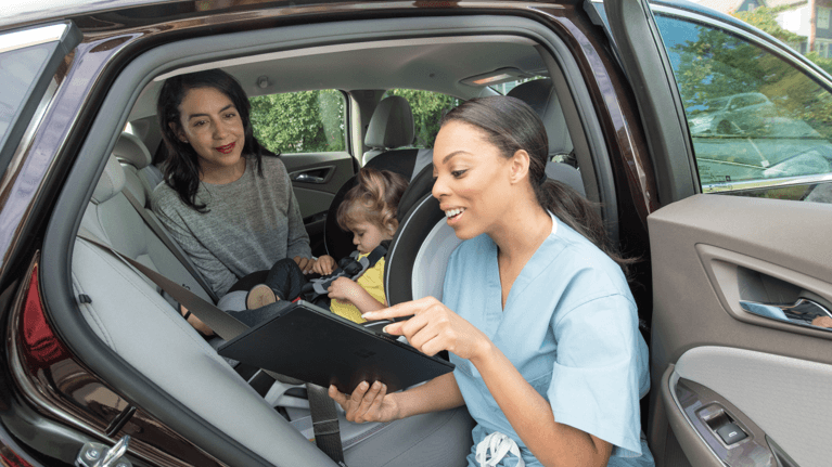 expert holding an owners manual showing a mom how to install a car seat with baby