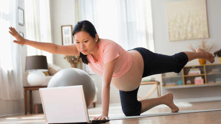 pregnant woman doing a yoga class while looking at a computer screen