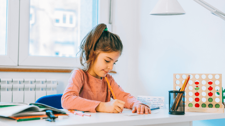little girl sitting at a table working on homework