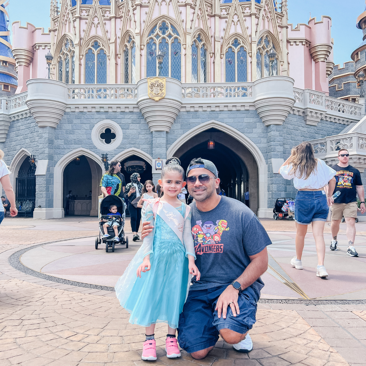 author Megan's daughter and husband in front of cinderella's castle after going to the bibbidi bobbidi boutique